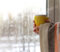 unrecognizable man in a blanket with a mug in his hands against the background of a window with raindrops on a cold day